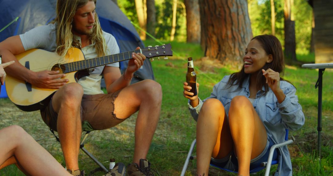 Friends Enjoying Campfire Music in Scenic Forest Setting - Free Images, Stock Photos and Pictures on Pikwizard.com