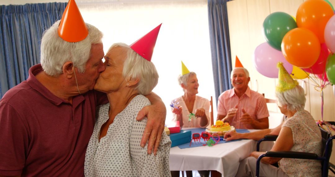 Senior couple kissing and hugging while celebrating birthday with friends at home  - Free Images, Stock Photos and Pictures on Pikwizard.com