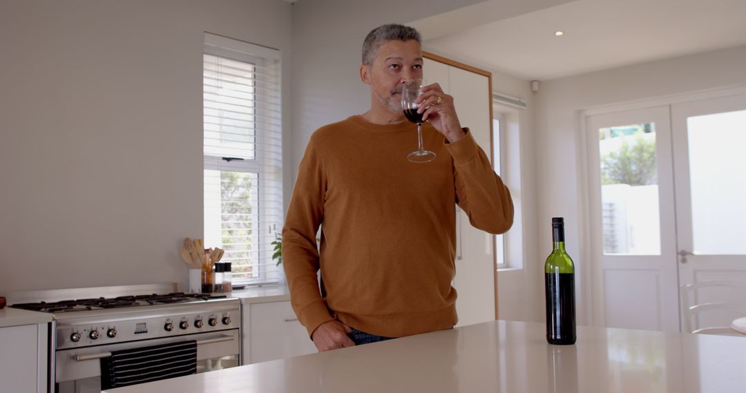 Senior Man Enjoying Wine in Bright Modern Kitchen Setting