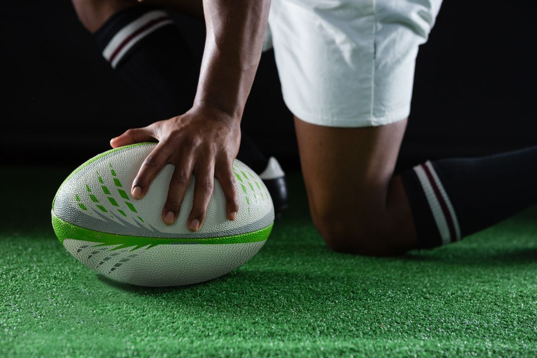 Side view of sportsman kneeling while holding rugby ball - Free Images, Stock Photos and Pictures on Pikwizard.com