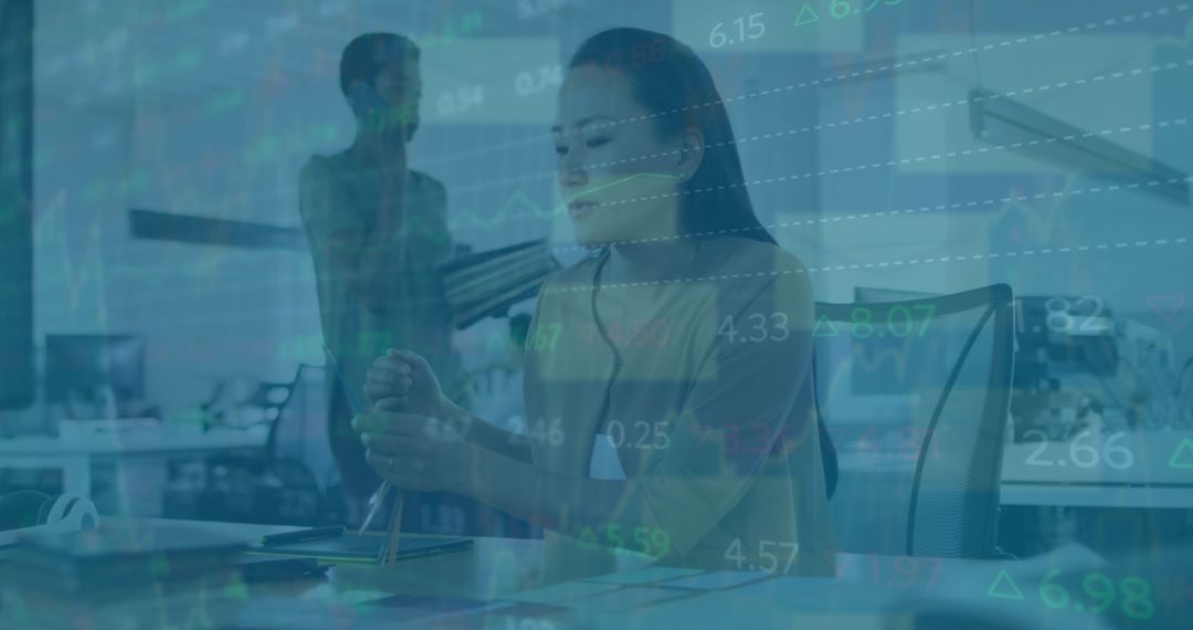Multitasking Businesswoman Working Amid Financial Data Overlay