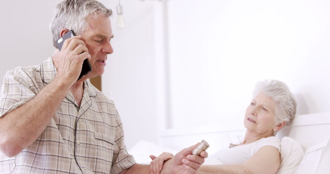 Senior man on phone call holding pills for sick wife in bed - Free Images, Stock Photos and Pictures on Pikwizard.com