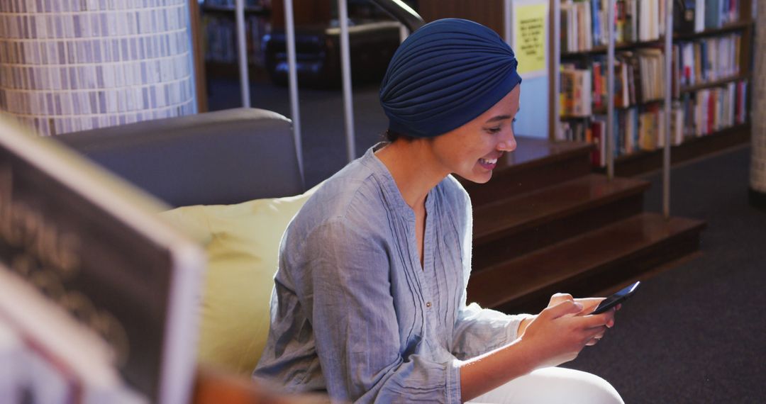 Woman in Blue Turban Using Smartphone in Cozy Library - Free Images, Stock Photos and Pictures on Pikwizard.com