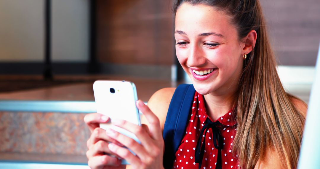 Joyful Young Woman Smiling While Using Smartphone Indoors