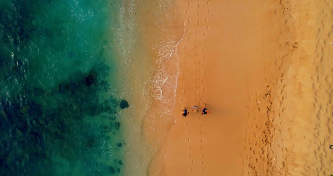 Aerial View of Two People Walking on Sandy Beach with Clear Ocean Waters - Free Images, Stock Photos and Pictures on Pikwizard.com