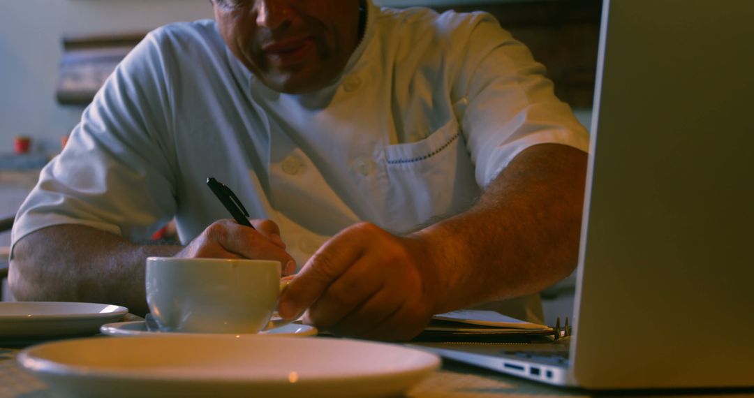 Chef Writing Notes with Coffee Cup and Laptop - Free Images, Stock Photos and Pictures on Pikwizard.com