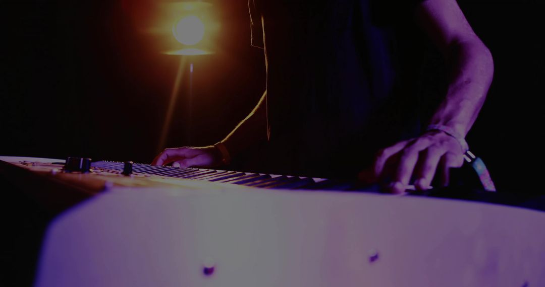 Silhouette of Musician Playing Electronic Keyboard in Dim Studio
