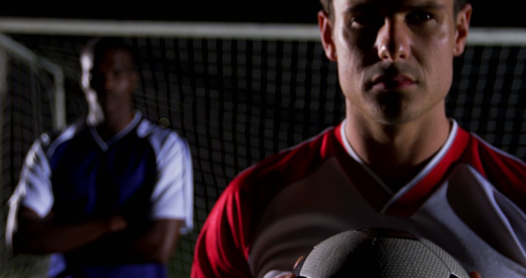 Focused Soccer Player Holding Ball on Field at Night - Free Images, Stock Photos and Pictures on Pikwizard.com