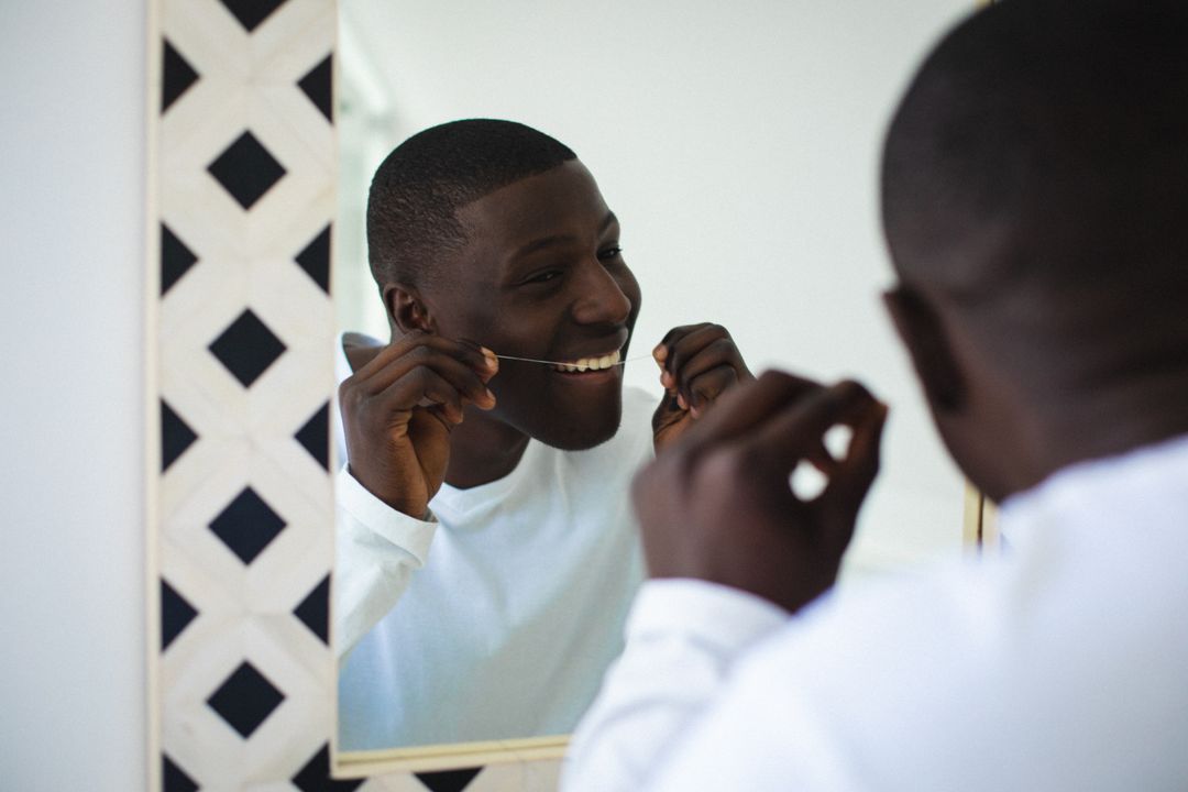 Young African American Man Flossing Teeth in Bathroom Mirror - Free Images, Stock Photos and Pictures on Pikwizard.com