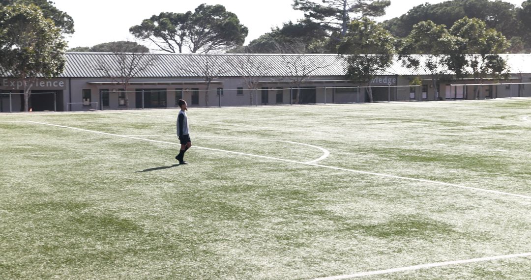 Youth Soccer Player on Empty Field Under Sunlit Sky