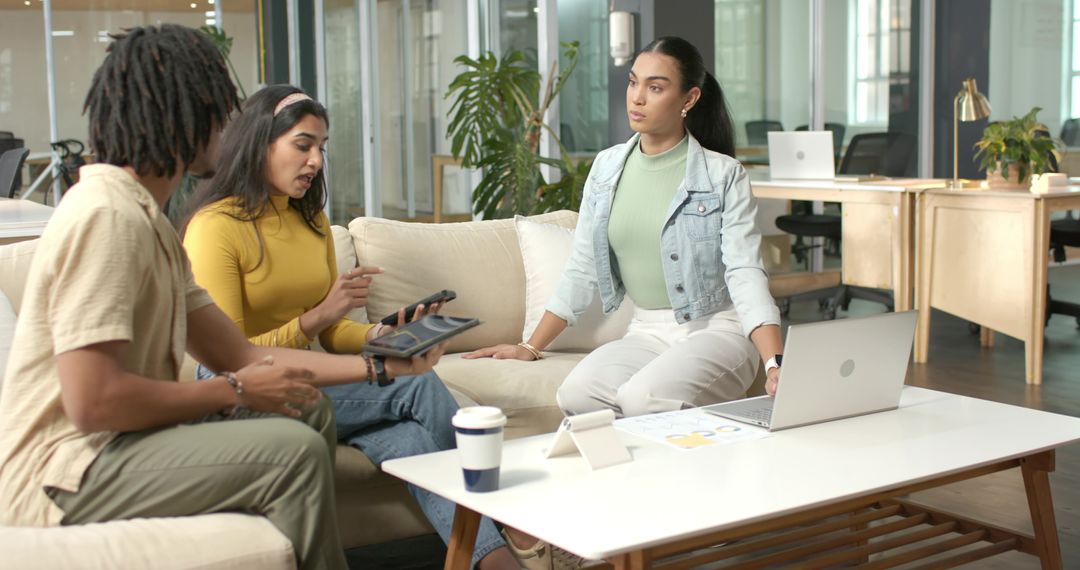 Diverse team collaborating in modern office lounge with Indian woman presenting tablet