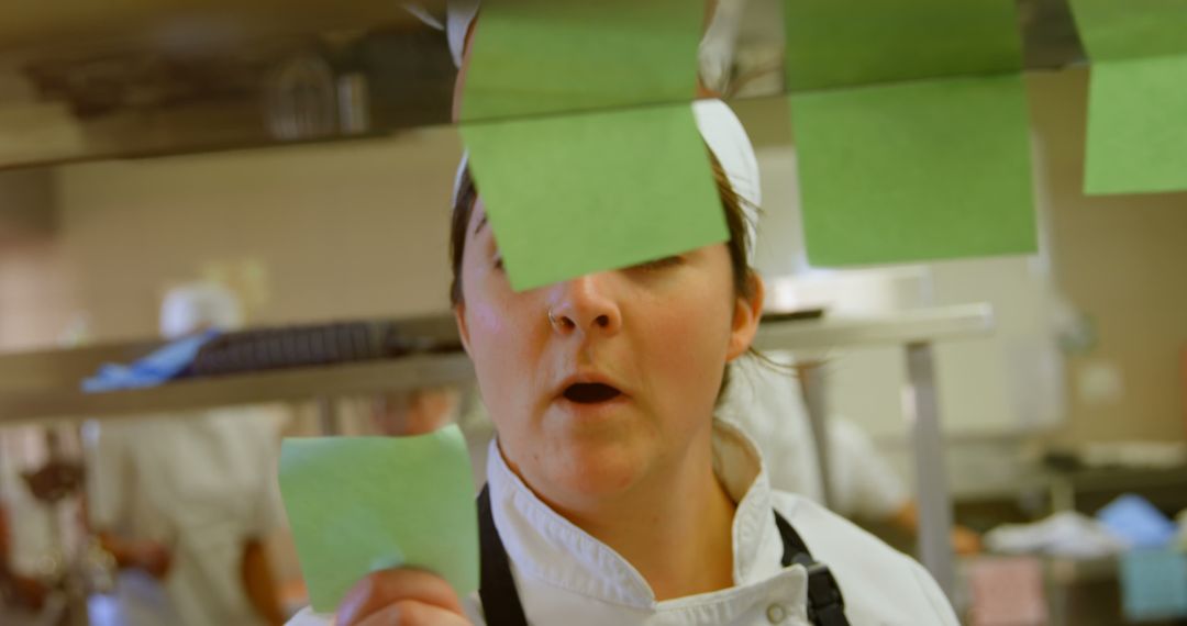 Female Chef Reading Order Tickets in Busy Professional Kitchen