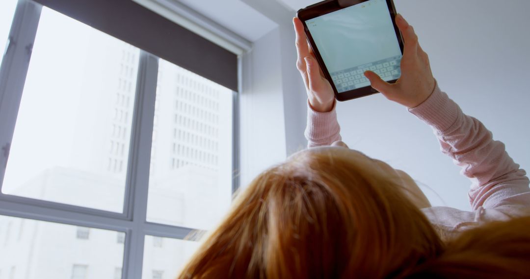 Person Lying Down Using Tablet Near Large Window - Free Images, Stock Photos and Pictures on Pikwizard.com