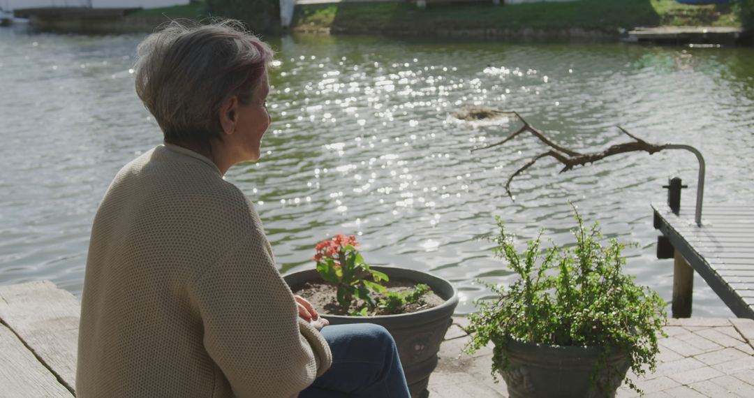 Elderly Woman Relaxing by Lakeside on a Sunny Day - Free Images, Stock Photos and Pictures on Pikwizard.com