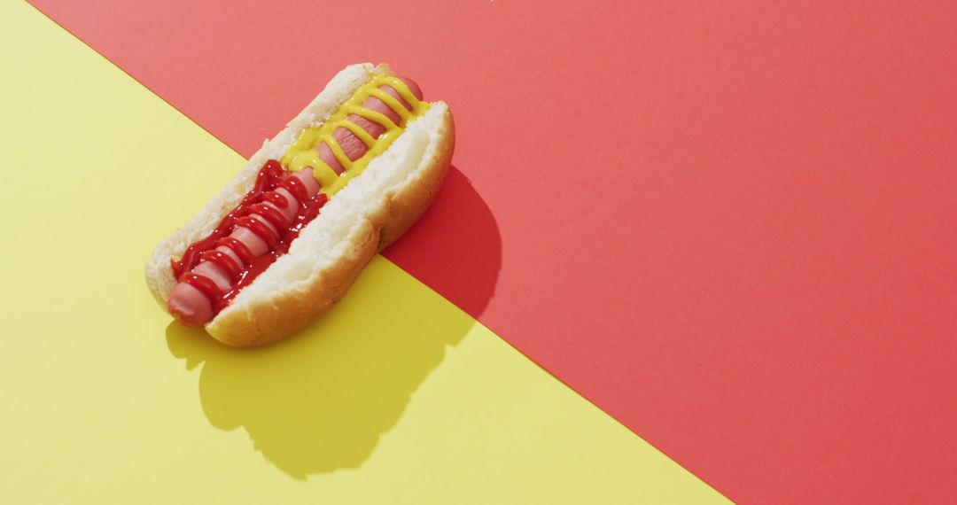 Image of hot dog with mustard and ketchup on a yellow and red surface - Free Images, Stock Photos and Pictures on Pikwizard.com