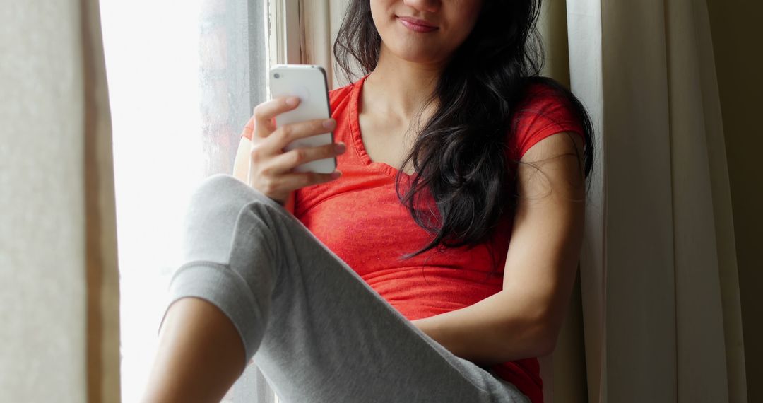 Young Woman Relaxing on Windowsill Using Smartphone - Free Images, Stock Photos and Pictures on Pikwizard.com