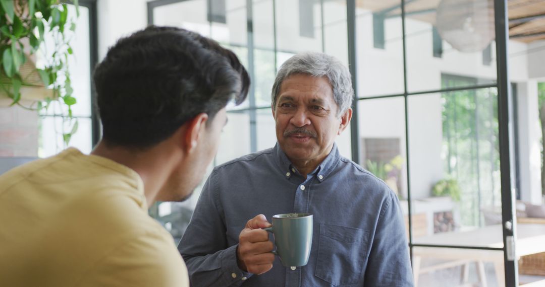 Senior Man Having Conversation with Young Adult over Coffee in Modern Home - Free Images, Stock Photos and Pictures on Pikwizard.com