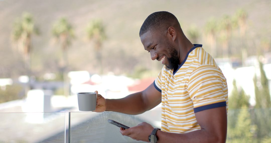 Smiling Man on Balcony Checking Smartphone with Hillside View