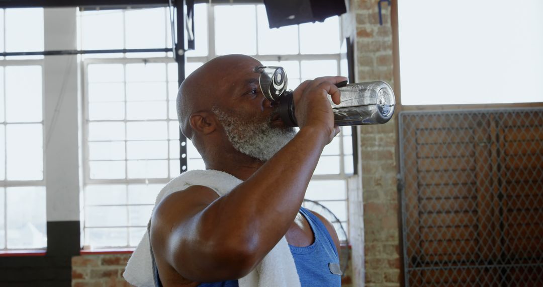 Elderly man hydrating during workout in gym - Free Images, Stock Photos and Pictures on Pikwizard.com