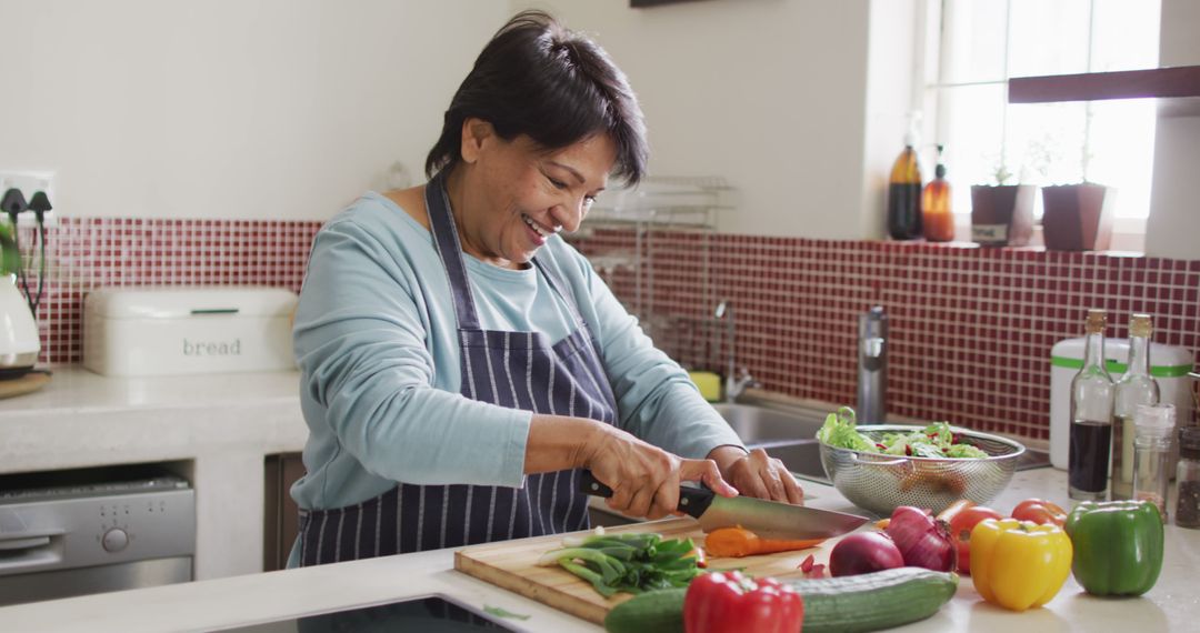 Smiling Senior Woman Preparing Fresh Salad in Modern Kitchen - Free Images, Stock Photos and Pictures on Pikwizard.com