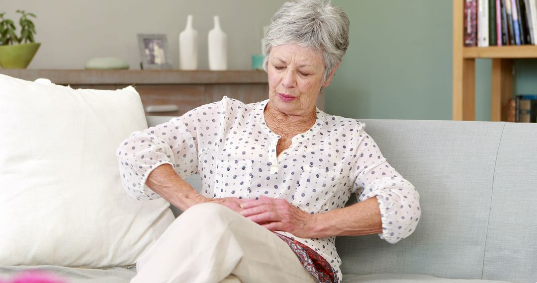 Senior Woman Experiencing Abdominal Pain on Couch - Free Images, Stock Photos and Pictures on Pikwizard.com