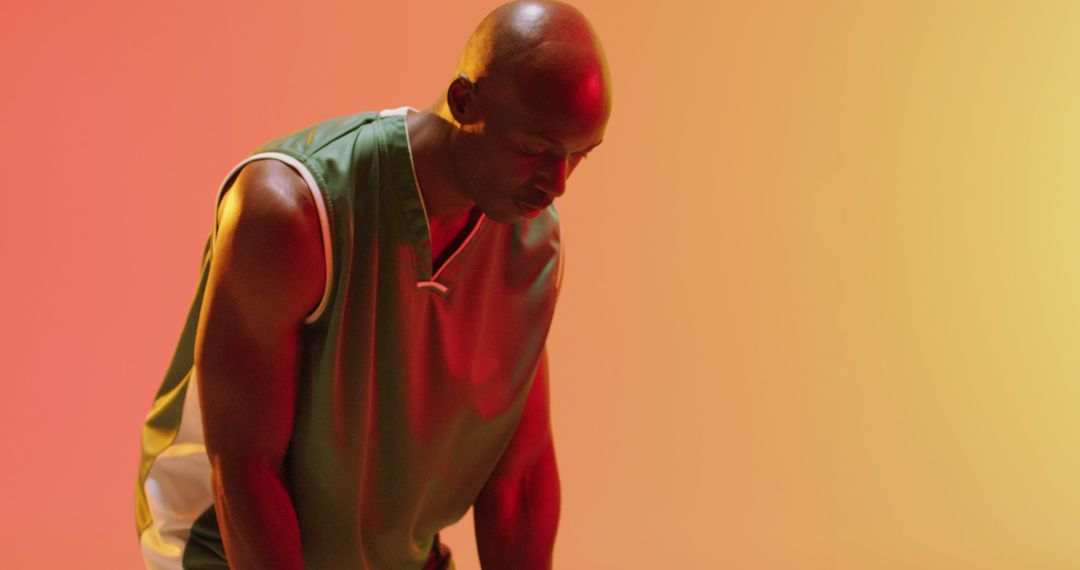 African American man wearing basketball jersey with intense focus in dramatic light - Free Images, Stock Photos and Pictures on Pikwizard.com