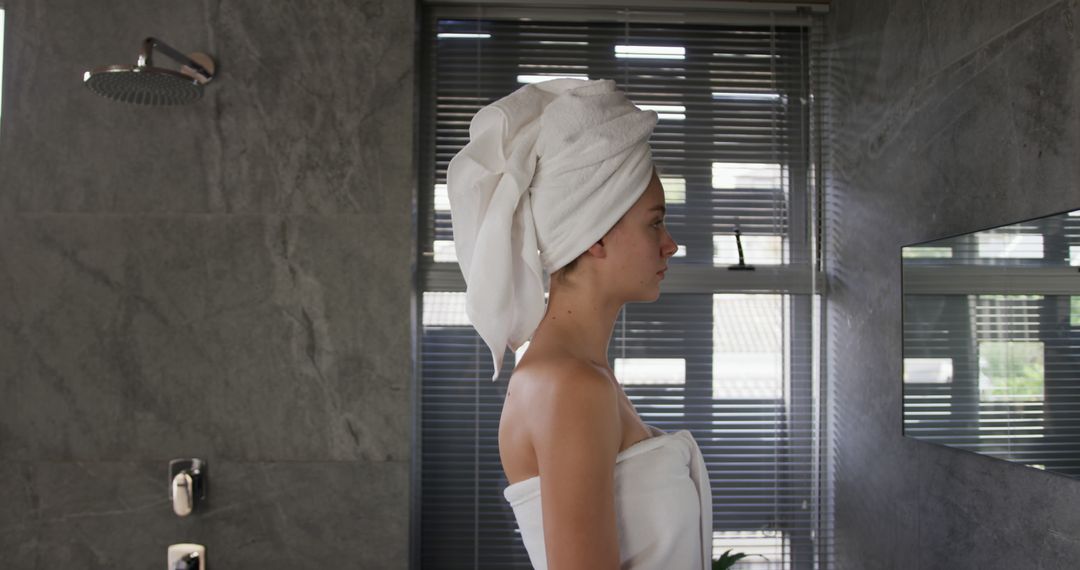 Woman with Towel on Head in Modern Bathroom Looking at Mirror - Free Images, Stock Photos and Pictures on Pikwizard.com