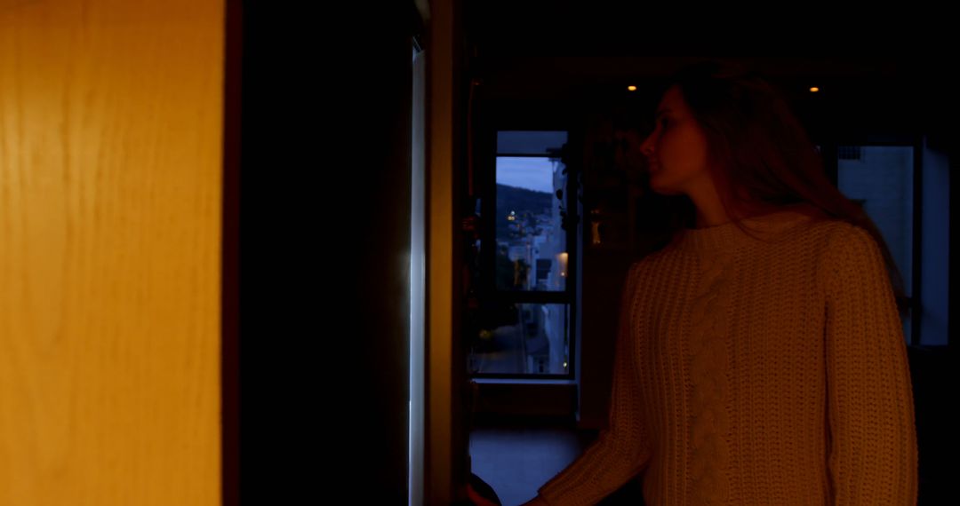 Woman in Warm Sweater Entering Dimly Lit Room at Dusk - Free Images, Stock Photos and Pictures on Pikwizard.com