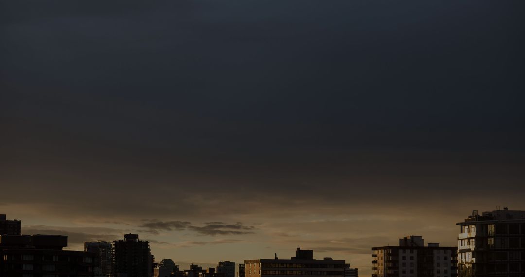Dense Clouds Looming Over Urban Skyline at Sunset