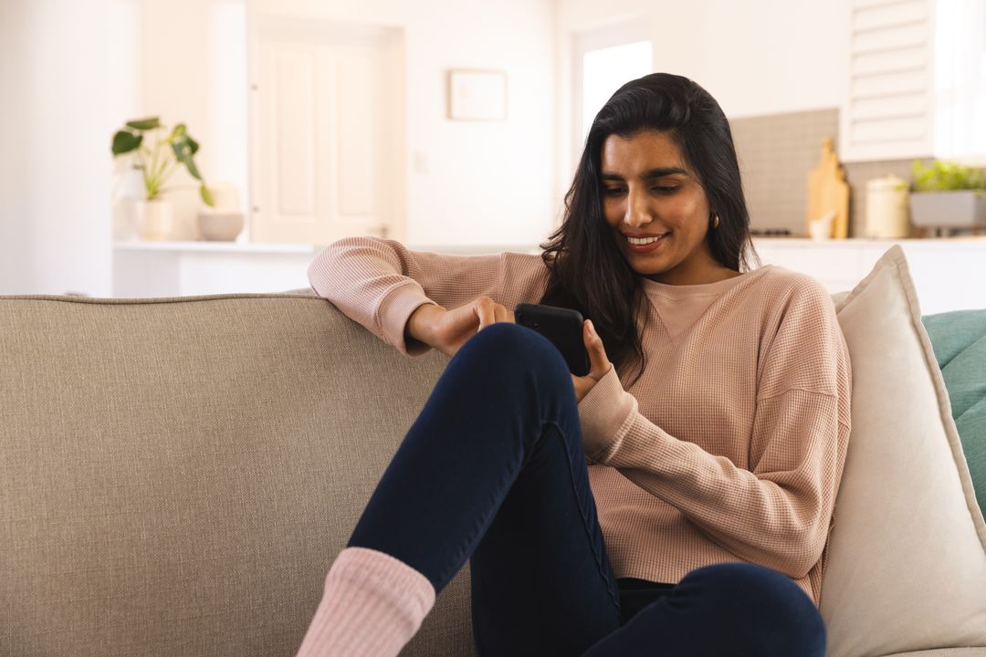 Woman Relaxing on Sofa While Using Smartphone in Cozy Living Room