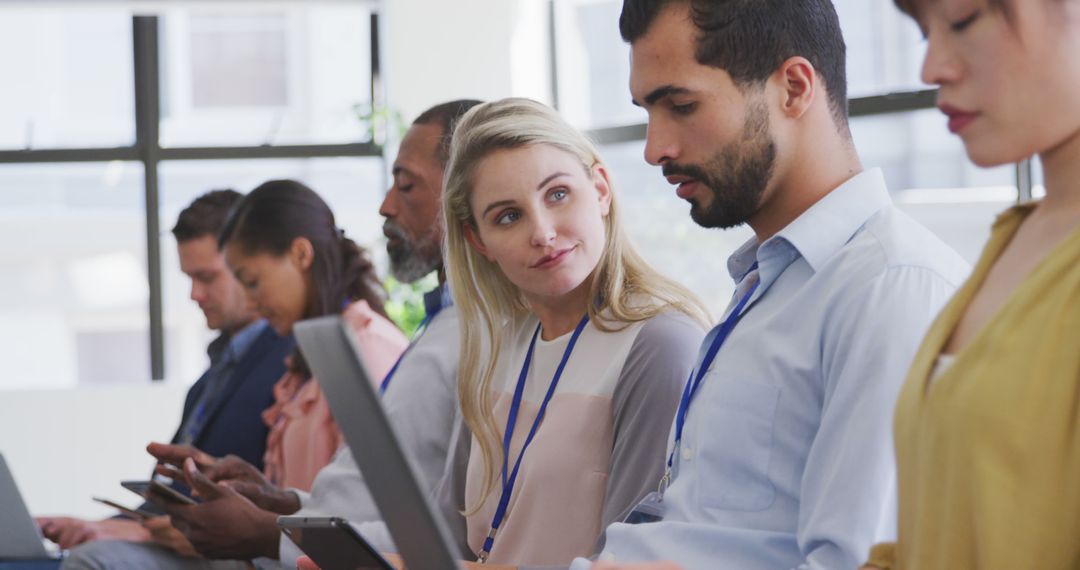 Colleagues Engaged in Meeting Using Laptops and Tablets in Office Setting
