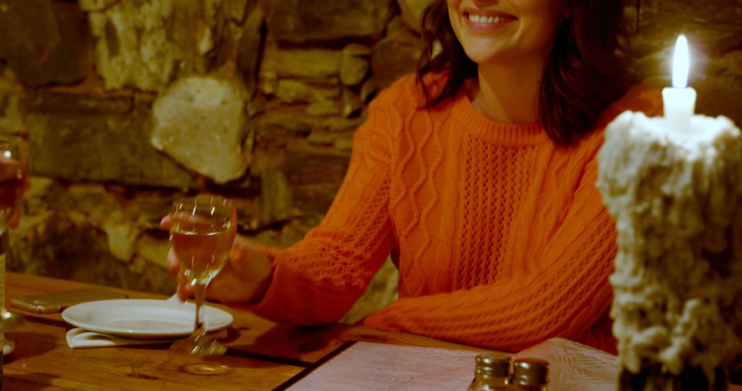 Happy caucasian woman sitting with glass next to candle and smiling in restaurant - Free Images, Stock Photos and Pictures on Pikwizard.com