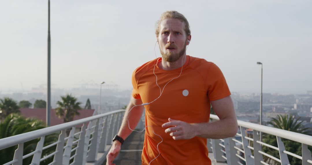 Blonde Man Jogging on Urban Bridge Wearing Orange Shirt - Free Images, Stock Photos and Pictures on Pikwizard.com
