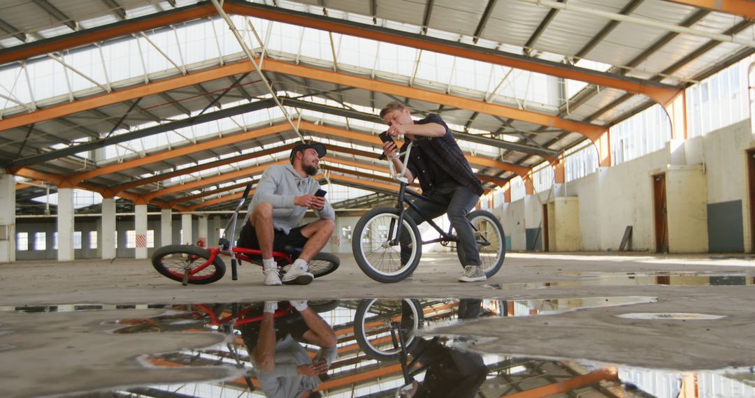 Two Friends Practicing BMX Tricks in Abandoned Warehouse - Free Images, Stock Photos and Pictures on Pikwizard.com