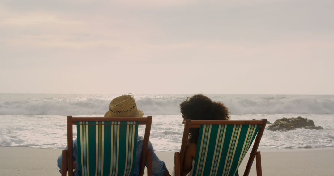 Couple Relaxing on Beach Loungers Facing Ocean Waves