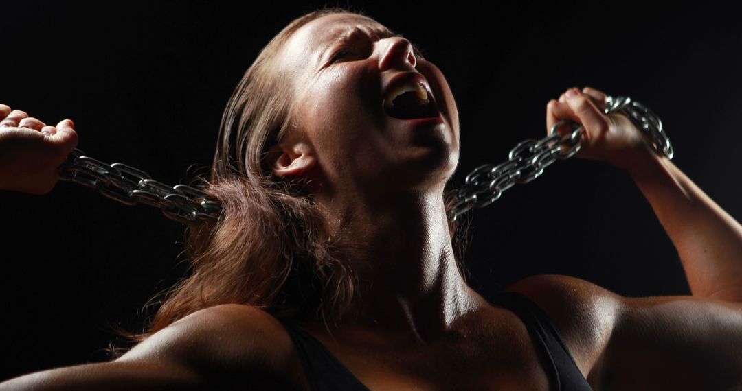 Woman Straining to Break Chains in Low Light - Free Images, Stock Photos and Pictures on Pikwizard.com