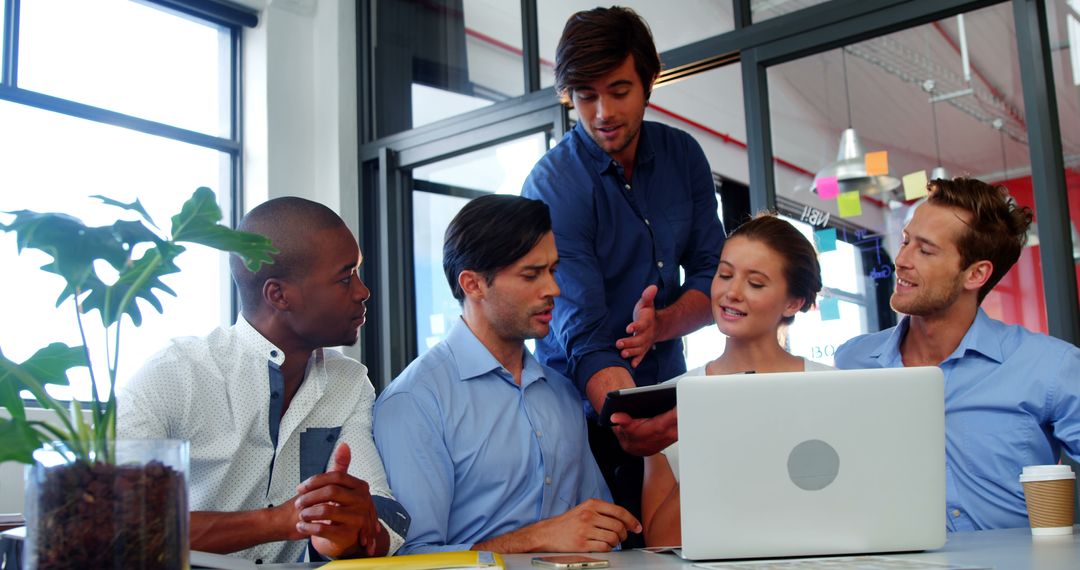 Business Team Collaborating Using Tablet and Laptop in Modern Office