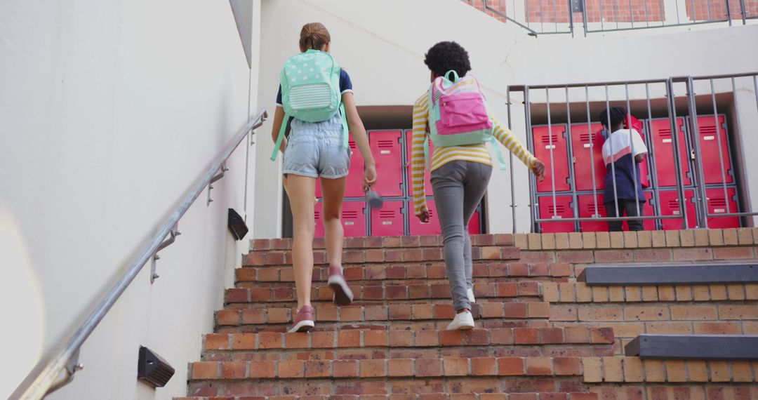 Schoolgirls with Backpacks Climbing Stairs Towards Lockers