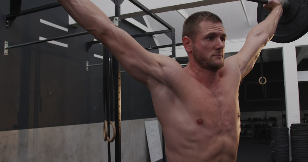 Muscular Man Weightlifting Barbell in Gym Focused Workout