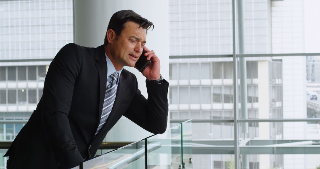 Businessman Leaning on Railing Talking on Smartphone in Modern Office - Free Images, Stock Photos and Pictures on Pikwizard.com