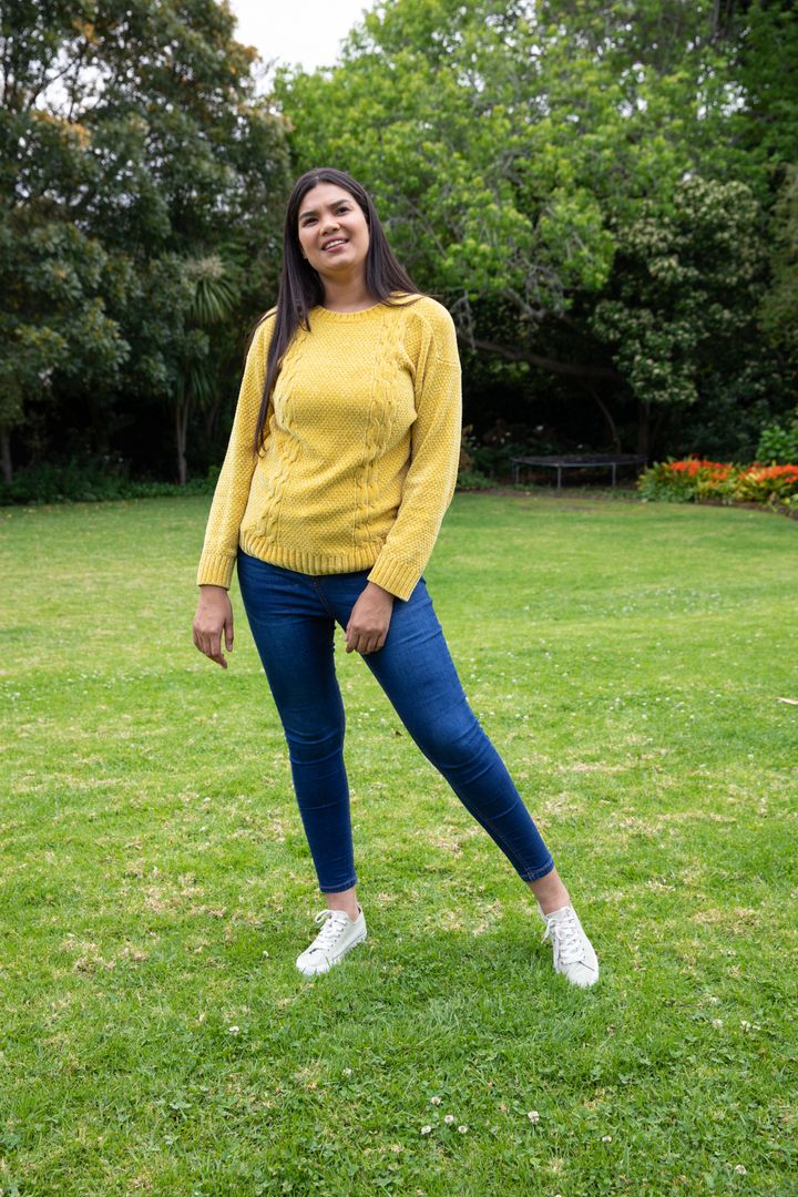 Smiling Woman in Mustard Sweater Enjoying Tranquil Garden
