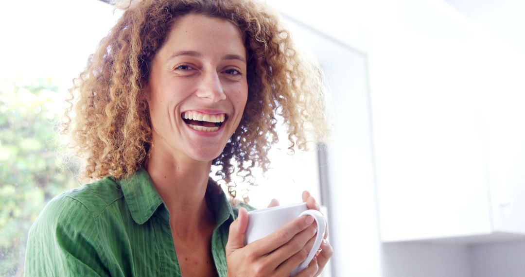 Smiling Woman Enjoying Coffee in Bright Kitchen - Free Images, Stock Photos and Pictures on Pikwizard.com