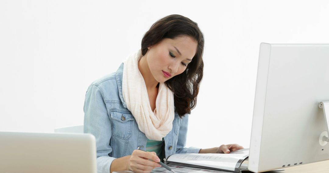 Focused Asian Woman Writing at Desk in Creative Office - Free Images, Stock Photos and Pictures on Pikwizard.com