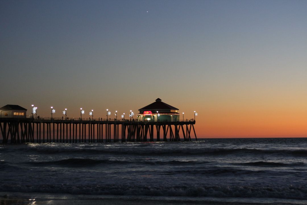 Sunset Over Huntington Beach Pier with Illuminated Lights and Calm Ocean - Free Images, Stock Photos and Pictures on Pikwizard.com