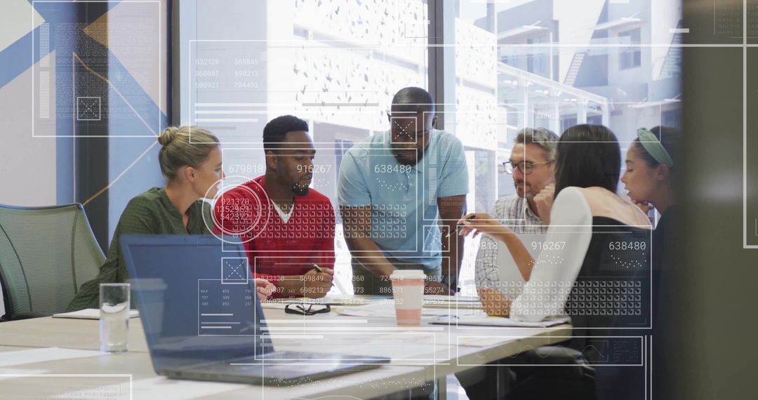 Diverse team collaborating over laptop during modern office brainstorming session