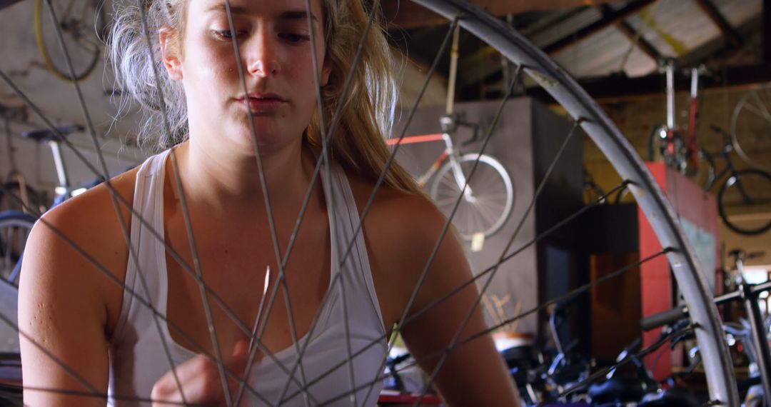 Focused Young Woman Repairing Bicycle Wheel in Workshop - Free Images, Stock Photos and Pictures on Pikwizard.com