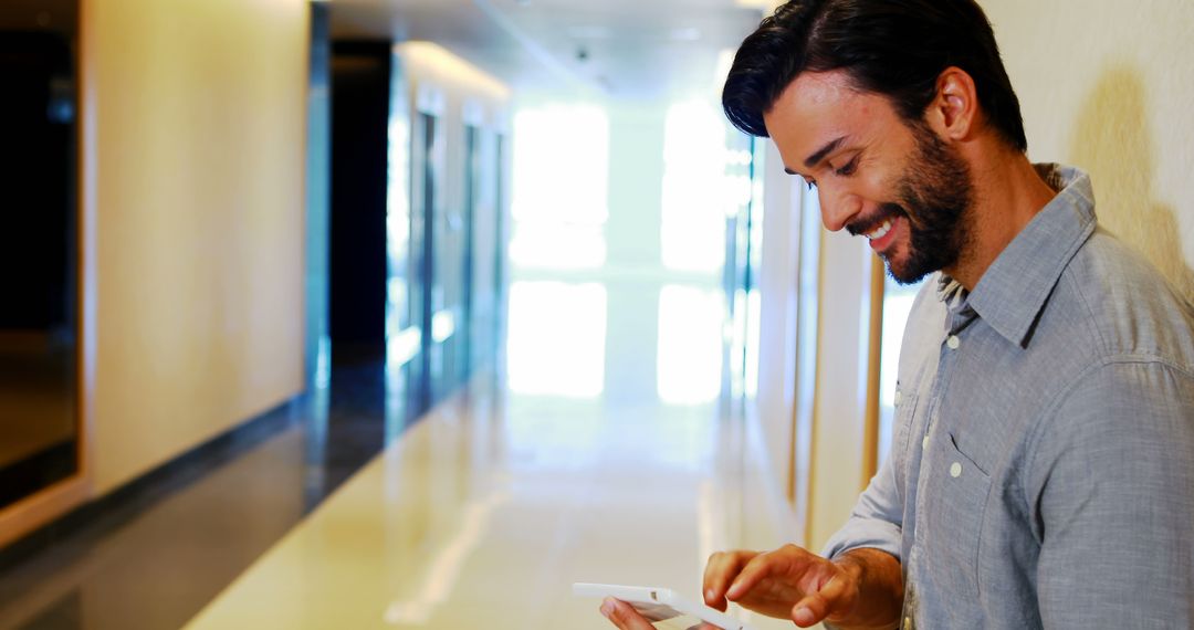 Smiling Businessman Using Tablet in Office Corridor