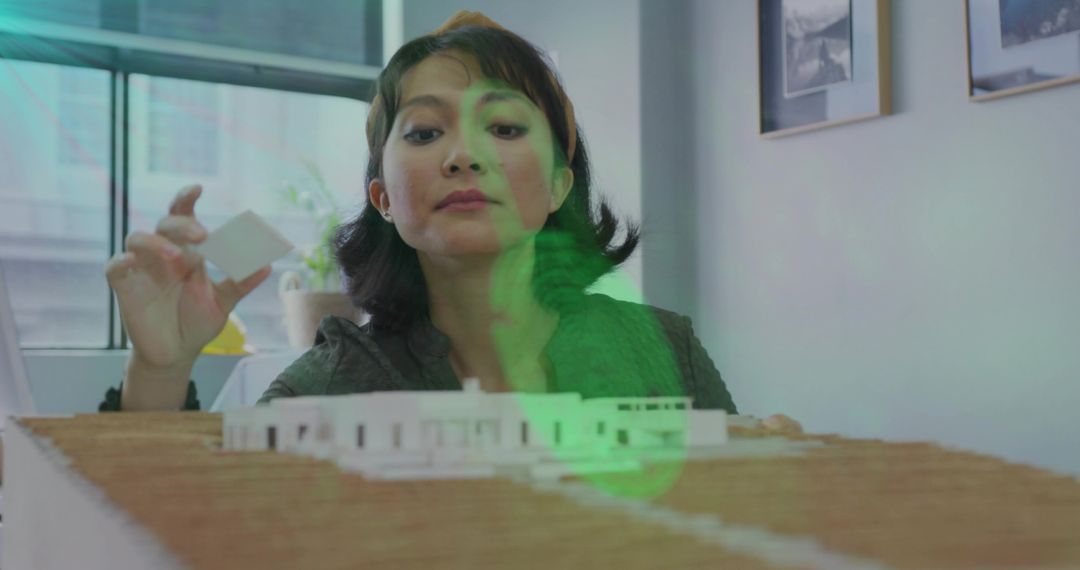 Asian Architect Placing Foam Block on Modern Architectural Model in Bright Design Studio