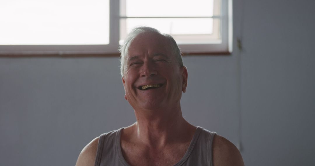 Cheerful senior man laughing in casual indoor setting - Free Images, Stock Photos and Pictures on Pikwizard.com