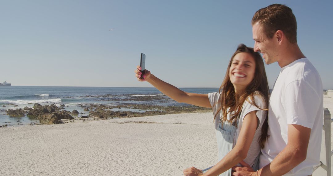 Smiling Couple Taking Selfie at Beautiful Beach on Sunny Day - Free Images, Stock Photos and Pictures on Pikwizard.com